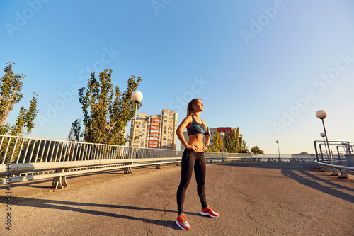 Girl runner before jogging on the road in the city in the summer autumn.