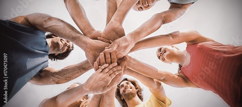 Friends standing with stacked hands against sky photo