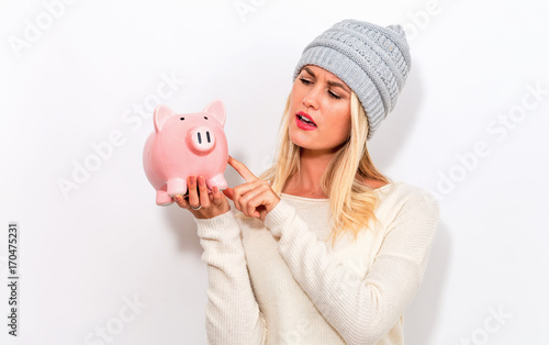 Young woman in winter clothes with a piggy bank