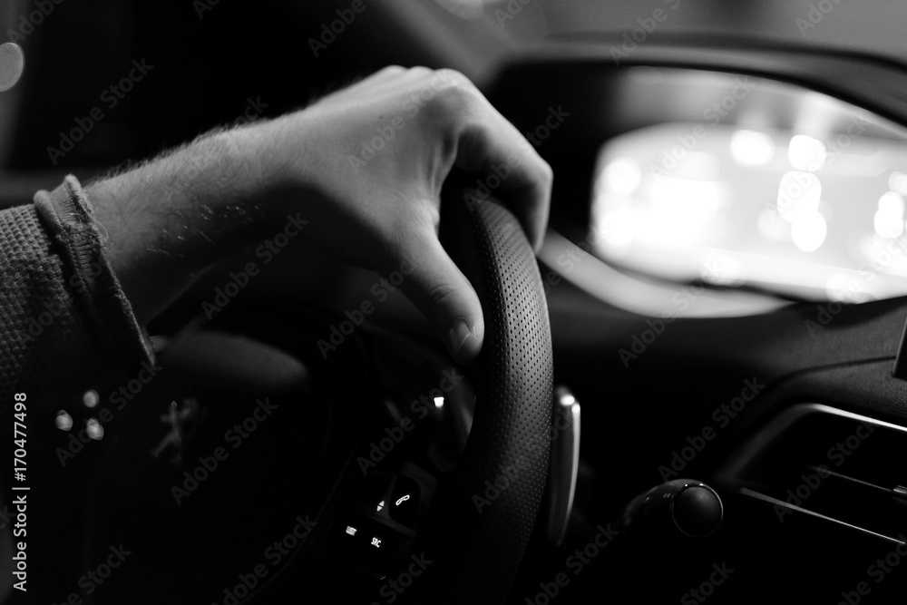 The driver's hand on the steering wheel in the car's interior