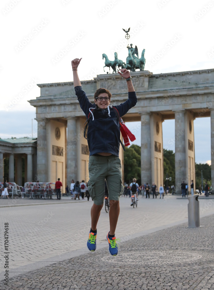 Fototapeta premium young boy makes a big leap in the Berlin square in front of the
