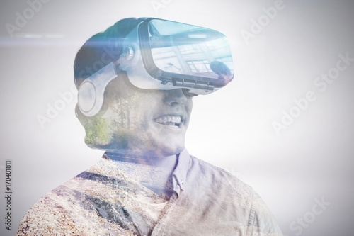 Composite image of smiling young man wearing virtual reality