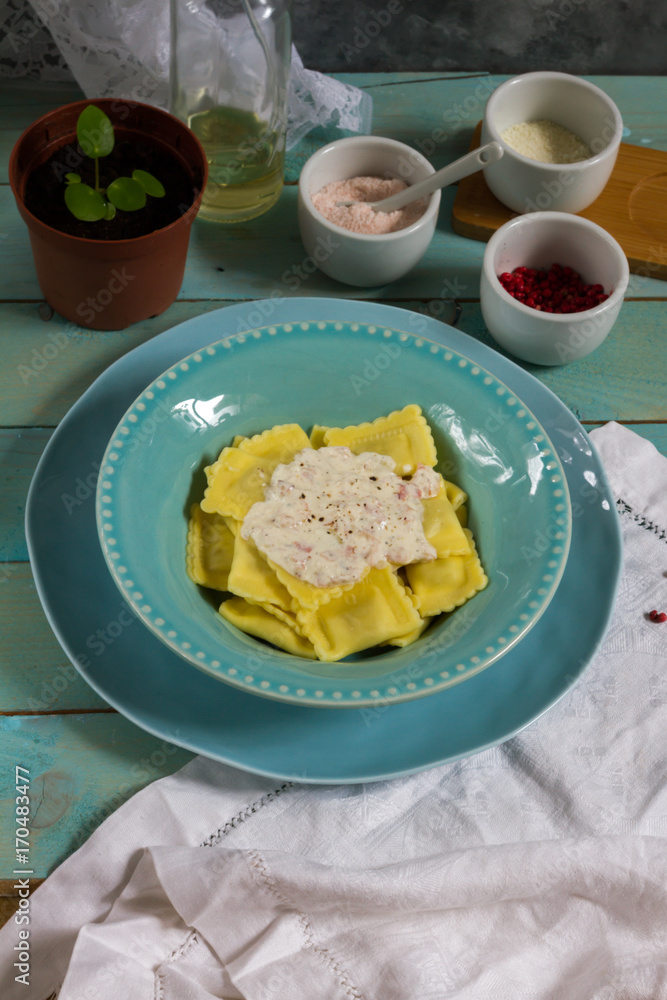 Ravioli with mushrooms and with bacon and sour cream sauce. Blue wooden table, blue plates. Ravioli with mushrooms and with bacon and sour cream sauce. Blue wooden table, blue plates.