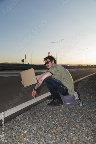Bild auf Leinwand Young man with empty piece of cardboard  hitchhiking