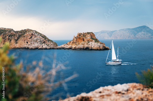 Sailboat with german flag are sailing at Mediterranean sea between cliffs and rocks against the stormy sky, Santa Ponsa, Mallorca, Spain