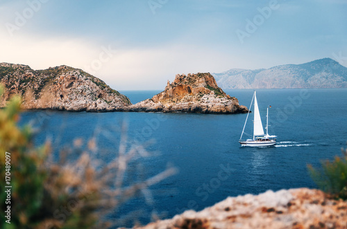 Sailboat with german flag are sailing at Mediterranean sea between cliffs and rocks against the stormy sky, Santa Ponsa, Mallorca, Spain photo