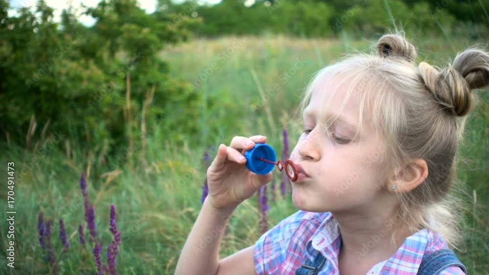 little girl blowing soap bubbles on a green lawn little girl blowing soap bubbles on a green lawn