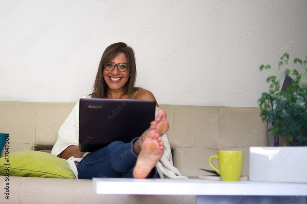 Mujer sentada en sofá trabajando en el computador Mujer sentada en sofá trabajando en el computador
