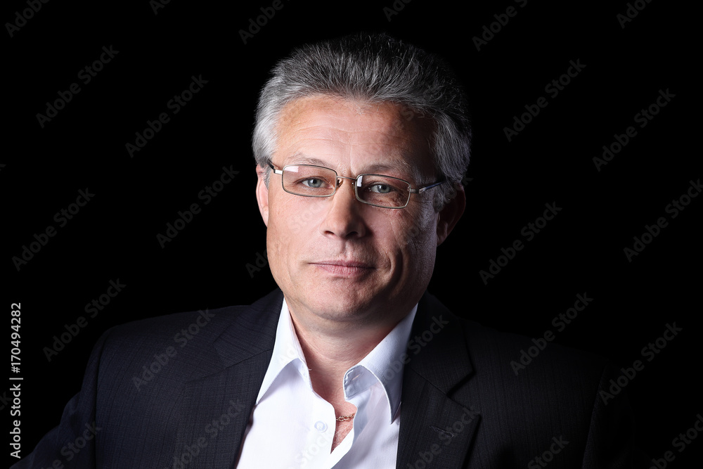 Gray-haired business man smiling isolated on black background. Gray-haired business man smiling isolated on black background.