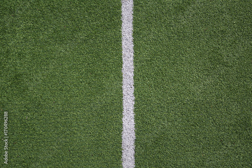 Green soccer grass field with white lines closeup. Concept out of play background. The line stands in the middle.