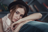 Portrait of a young beautiful girl in a home setting. Model leaned on the back of the couch