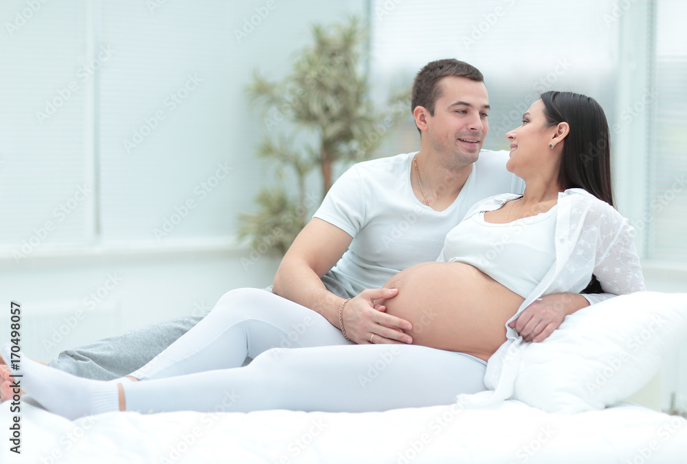 Pregnant woman with her husband relaxing at home Pregnant woman with her husband relaxing at home