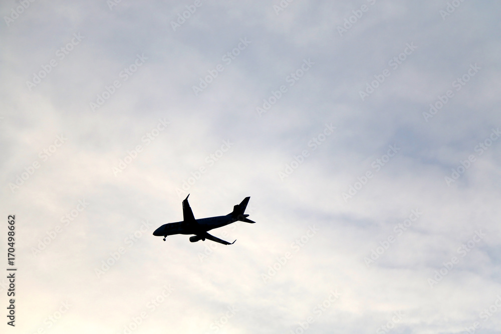 Plane silhouette on a cloudy sky. 
