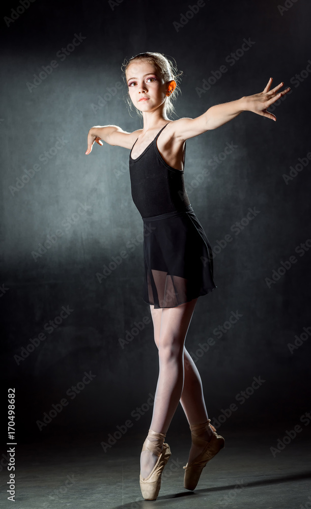 Young girl ballerina showing the dance elements on a dark background. Ballet.