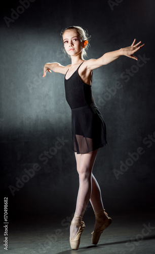 Young girl ballerina showing the dance elements on a dark background. Ballet.