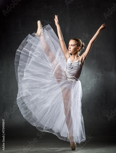 Young girl ballerina showing the dance elements on a dark background. Ballet.