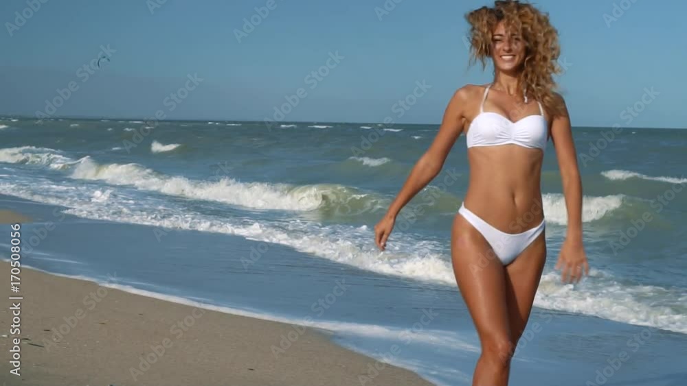 Young beautiful sexy tanned girl in swimsuit runs along the beach. Slow motion. Steadicam. Young beautiful sexy tanned girl in swimsuit runs along the beach. Slow motion. Steadicam.