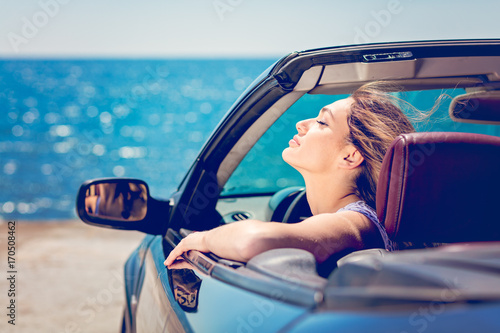 Obraz na plátně Happy and carefree woman in the car on the beach