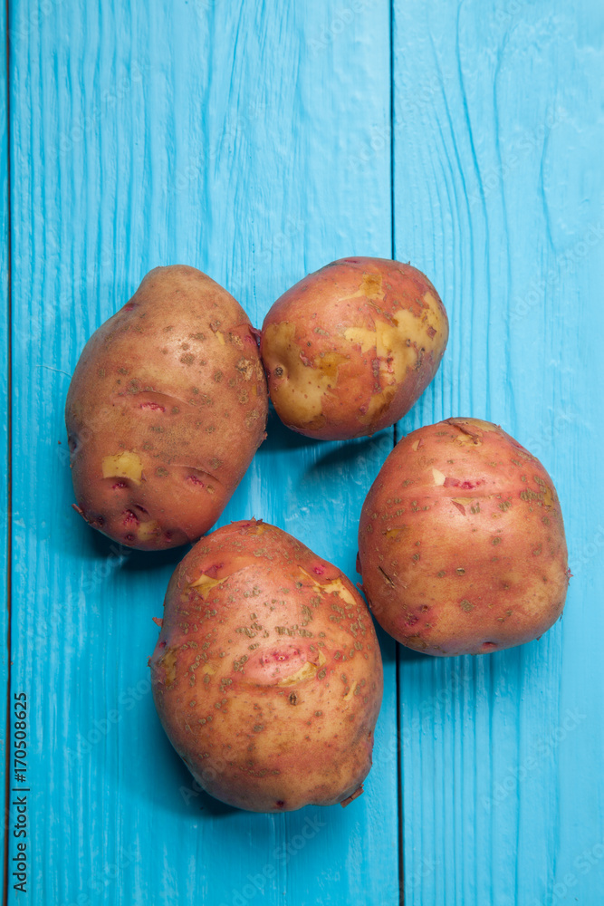 Raw potatoes on a blue wooden background Raw potatoes on a blue wooden background