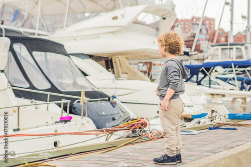 Cute blond boy looking at yachts and sailboats photo