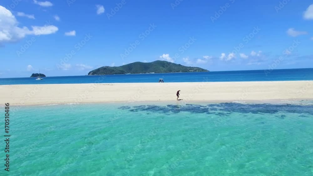 A wide shot of a sand bar and ocean with yacht and mountains A wide shot of a sand bar and ocean with yacht and mountains