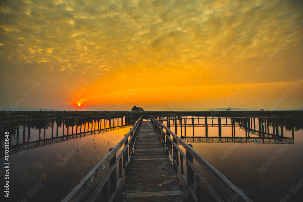Beautiful romantic golden sunset and wooden bridge at pond. Fantastic vivid twilight at Sam Roi Yod National Park, Prachuap Khirikhan, Thailand.