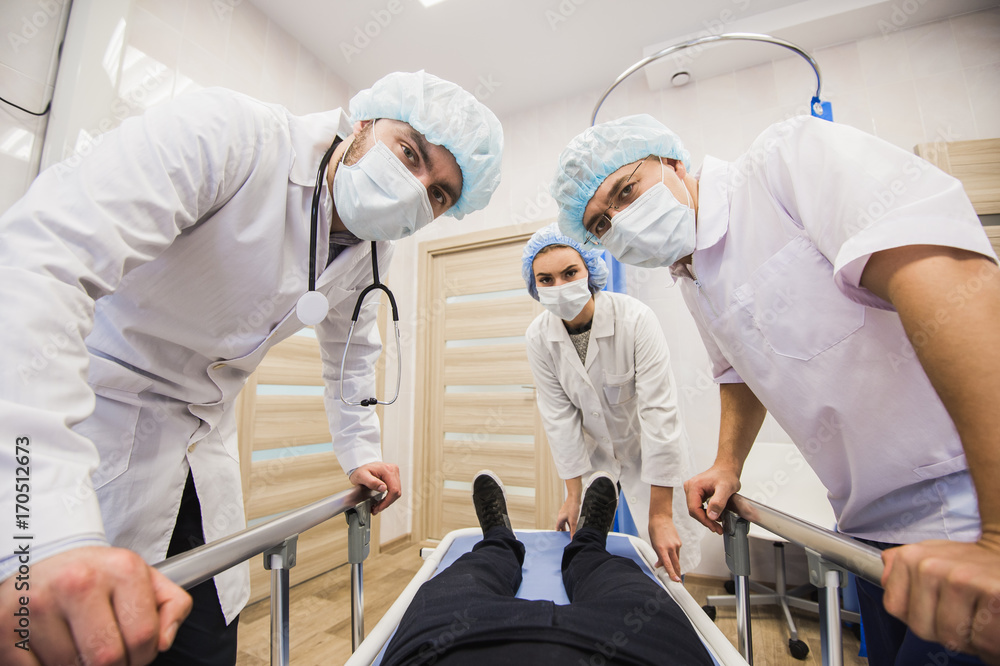 Fototapeta premium Sick patient on gurney in operating room with doctors in front of him.