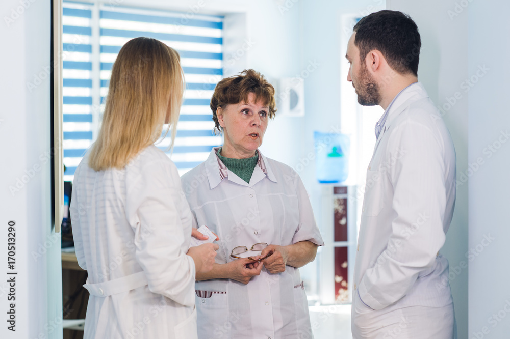 Obraz premium Mature doctor discussing with nurses in a hallway hospital. Doctor discussing patient case status with his medical staff after operation.