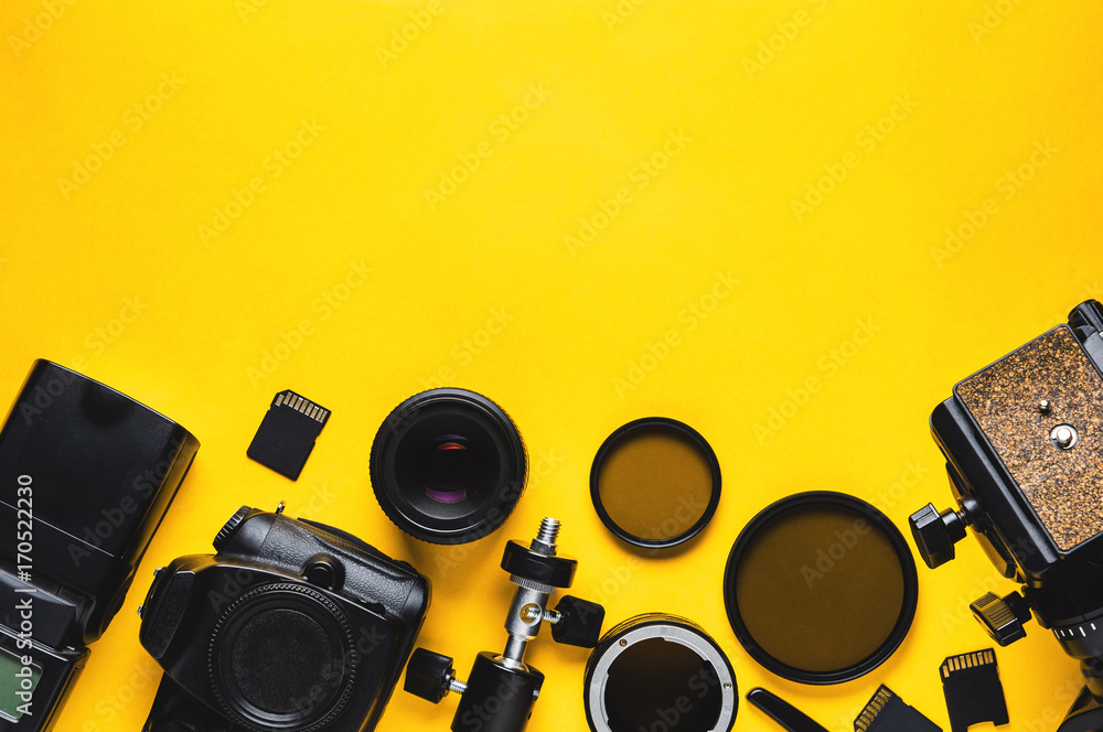 Digital camera, lenses and equipment of the photographer on a yellow background - obrazy, fototapety, plakaty 