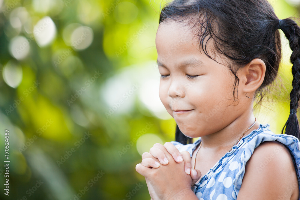 Cute asian little child girl praying with folded her hand for faith,spirituality and religion concept Cute asian little child girl praying with folded her hand for faith,spirituality and religion concept