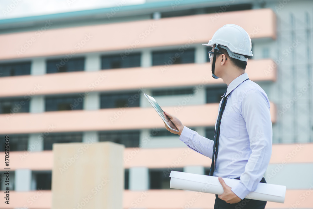 smiling young architect or engineering builder in hard hat with tablet over group of builders at construction site, architect watching some a construction, business, building, industry, people concept smiling young architect or engineering builder in hard hat with tablet over group of builders at construction site, architect watching some a construction, business, building, industry, people concept
