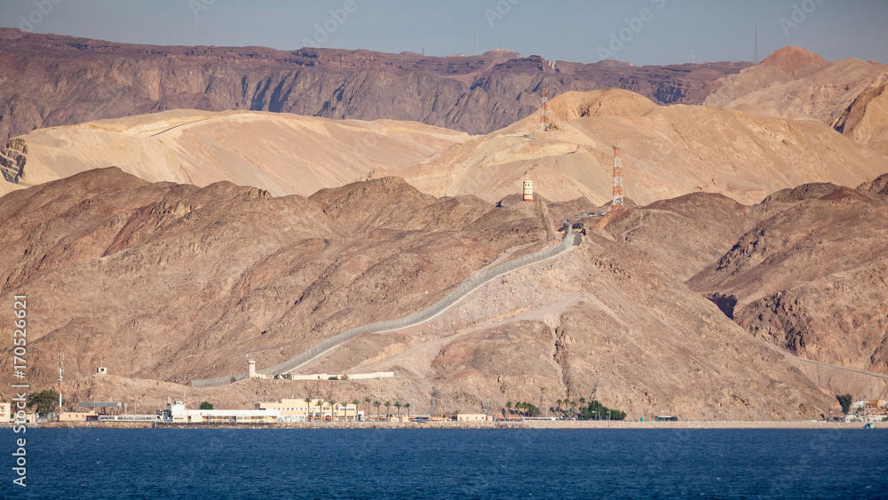 Coastline landscape of the boarder between Egypt and Israel on the Red Sea in the Gulf of Aqaba. The fence is the boarderline. / Egypt and Israel Coastal Landscape