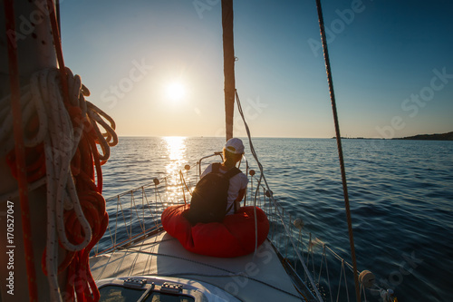 Young woman sitting on the bow of the yacht.