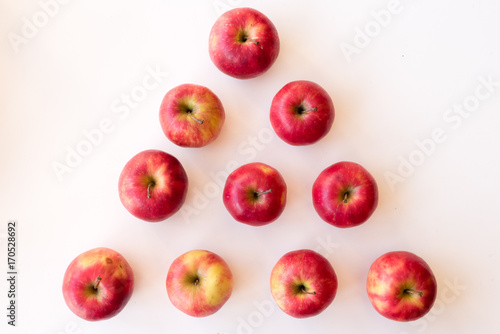 High angle view of organic pink lady apples arranged in a pyramid shape on white background