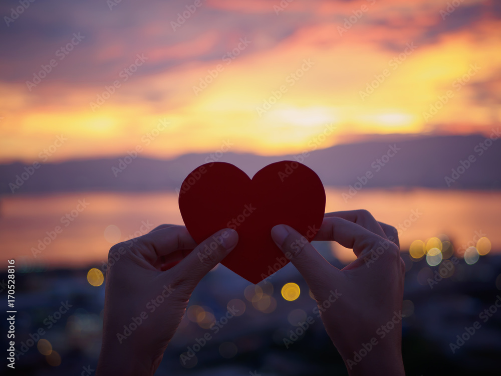 Silhouette hand holding beautiful heart during sunset background. Happy, Love, Valentine's day idea, sign, symbol, concept.