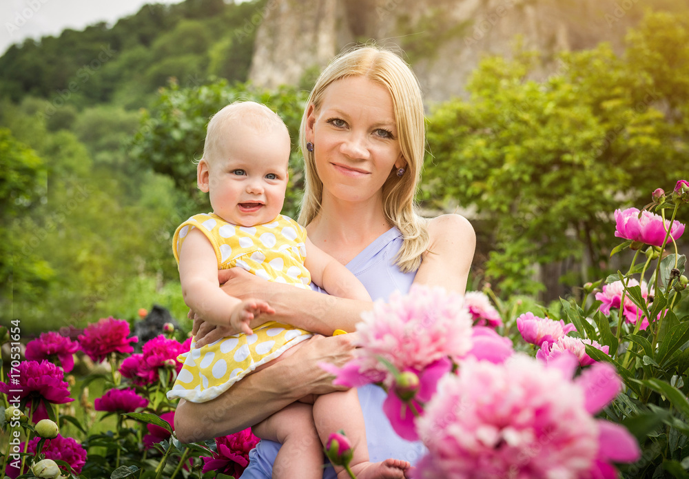 Happy woman and child in the blooming peony flowers Happy woman and child in the blooming peony flowers
