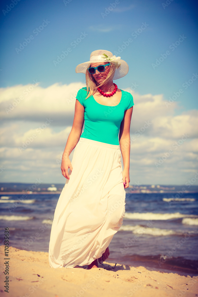 Blonde woman wearing dress walking on beach Blonde woman wearing dress walking on beach