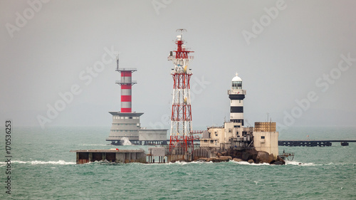 Horsburgh Lighthouse on Pedra Branca Island of Singapore and Abu Bakar Maritime Base owned by Malaysia in the Singapore Strait. photo