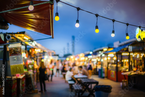 Behang Decorative outdoor string lights hanging on electricity post in the garden at night time with blur people