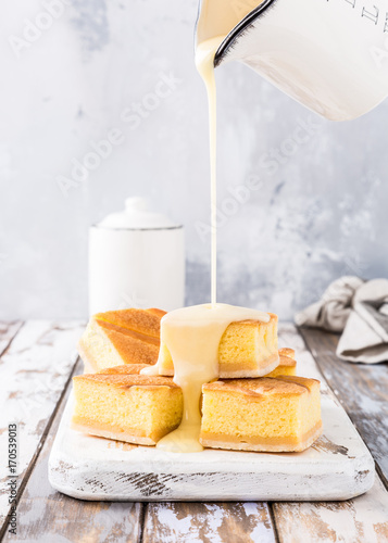 Fototapeta Traditional homemade baked pudding cake, custard cream is poured on pieces of cake