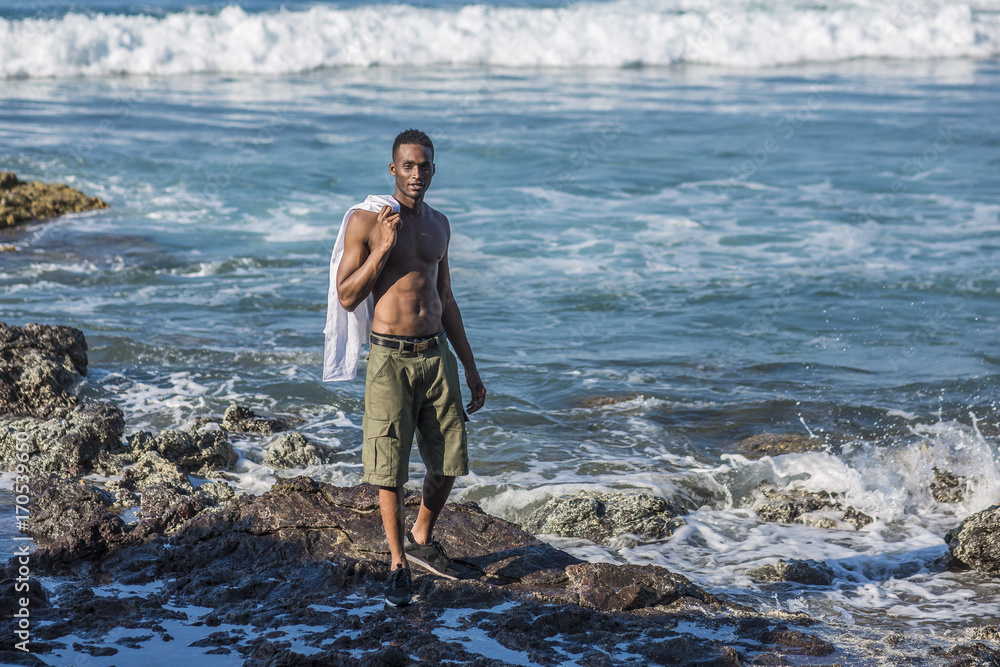 photo shoot for a black handsome guy on the rocky shore of the ocean