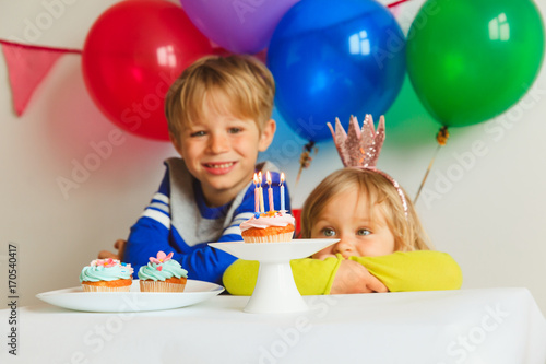 happy little girl and boy blowing candles at birthday party