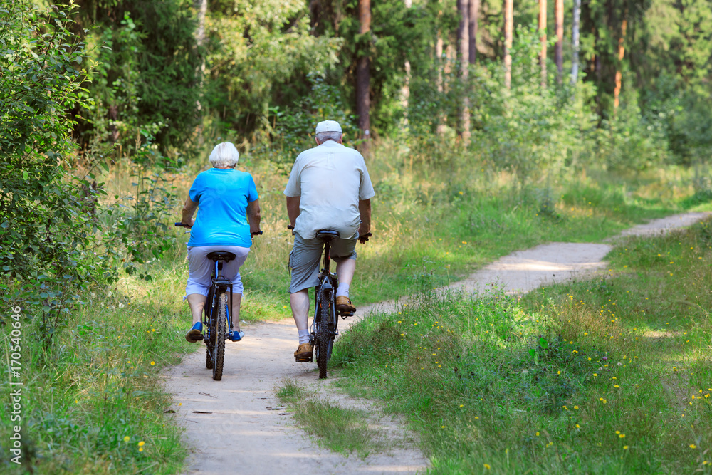 Naklejka premium active senior couple riding bikes in nature