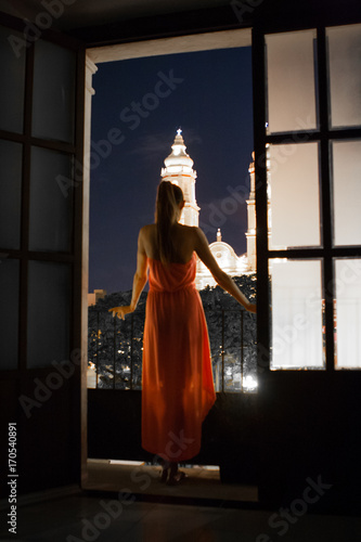 Woman looking out of a window at night, Campeche cathedral, Mexico.