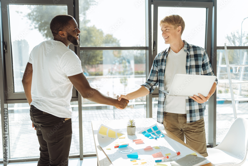 Obraz premium Positive colleagues shaking hands in the office