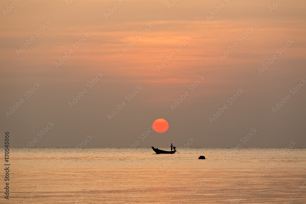 Silhouette of a local fisherman sailing the boat under a sundown Silhouette of a local fisherman sailing the boat under a sundown