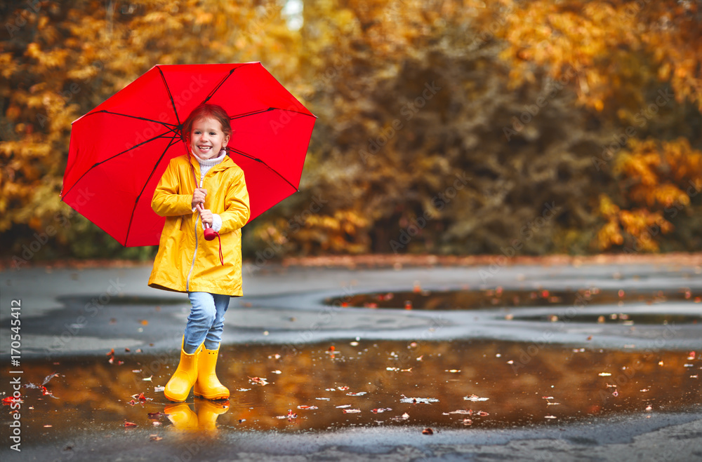 Obraz premium happy child girl with an umbrella and rubber boots on autumn walk.