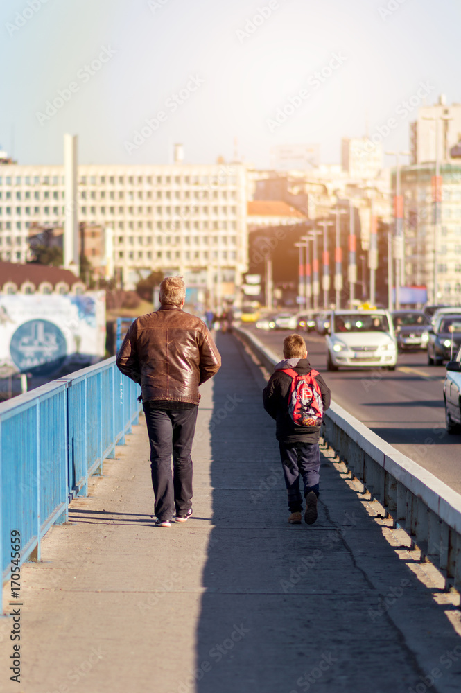 Father and his son walking across the bridge on a sunny day