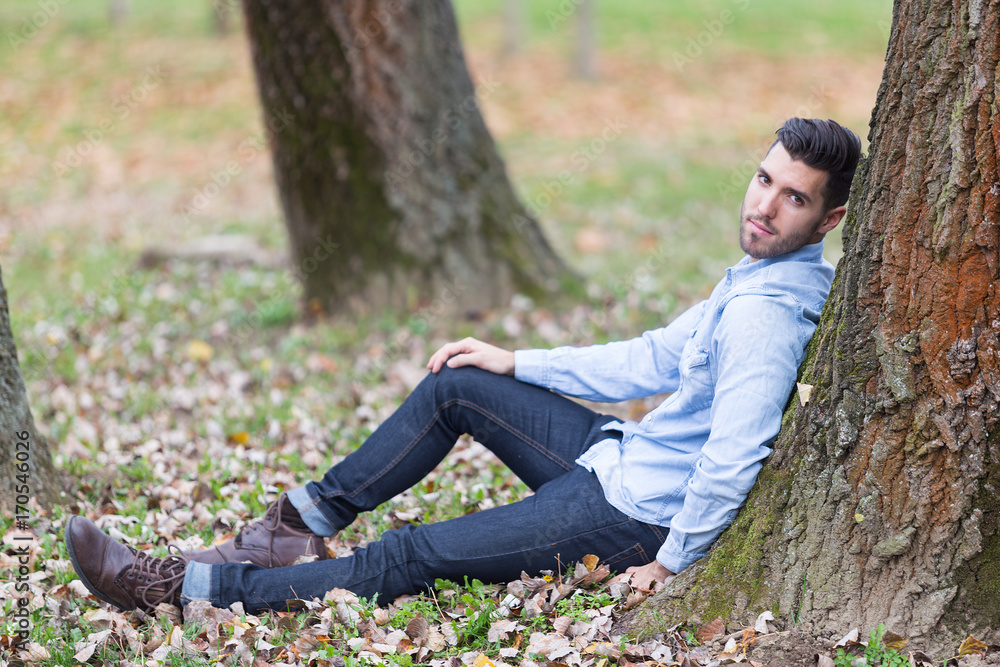 Handsome sad man in the park. Autumn scenery Handsome sad man in the park. Autumn scenery