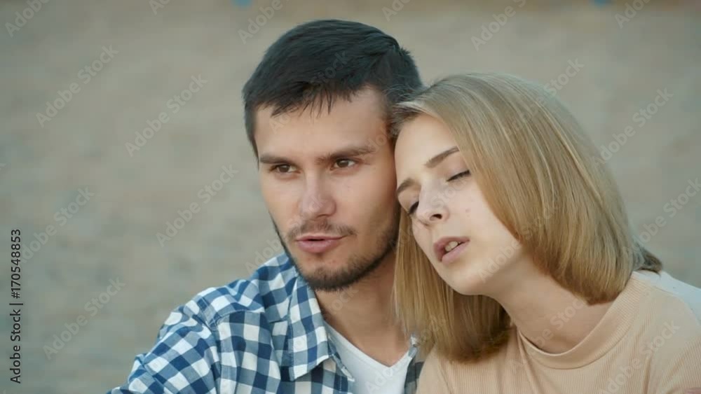 Slowmotion video a loving couple admiring the sunset sitting on the riverbank. The guy gently hugs the girl. Slowmotion video a loving couple admiring the sunset sitting on the riverbank. The guy gently hugs the girl.